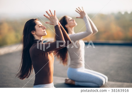 Two young beautiful women doing yoga asana on the roof outdoor Two young beautiful women doing yoga asana on the roof outdoor 38163916