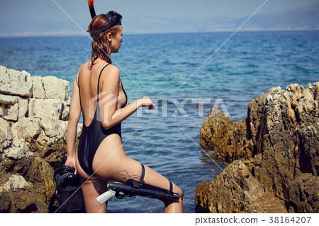 Young woman with a mask going to snorkel in clear sea Young woman with a mask going to snorkel in clear sea 38164207