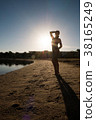Sweet girl stands on the beach against the sunset. 38165249
