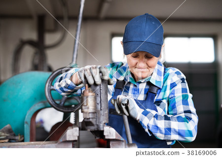 Senior female mechanic repairing a car in a garage 38169006