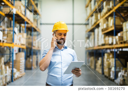 Warehouse worker or supervisor with a smartphone. 38169270