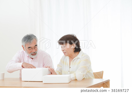 An elderly couple senior silver generation grandfather and grandmother opening a package happily An elderly couple senior silver generation grandfather and grandmother opening a package happily 38169727