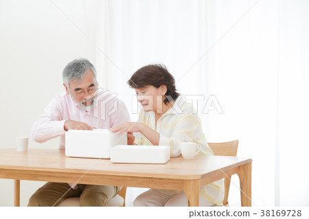 An elderly couple senior silver generation grandfather and grandmother opening a package happily An elderly couple senior silver generation grandfather and grandmother opening a package happily 38169728