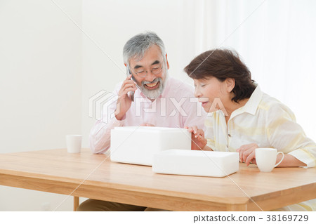 An elderly couple senior silver generation grandfather and grandmother opening a package happily An elderly couple senior silver generation grandfather and grandmother opening a package happily 38169729