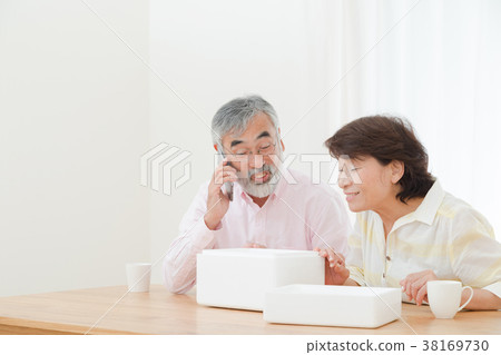 An elderly couple senior silver generation grandfather and grandmother opening a package happily An elderly couple senior silver generation grandfather and grandmother opening a package happily 38169730