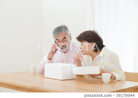 An elderly couple who is puzzled by opening a package Delivery problems Sending Herons Senior Silver Generation Grandpa and grandmother 38170044