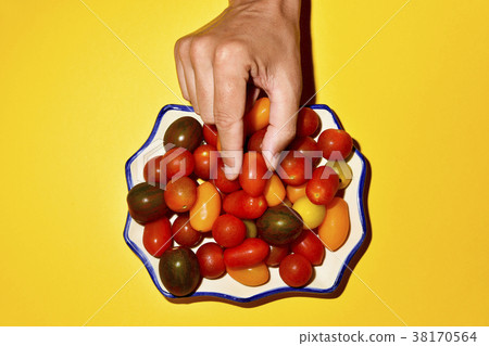 man picking a cherry tomato from a plate man picking a cherry tomato from a plate 38170564