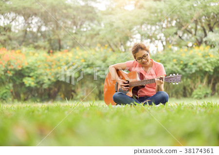 Female is sitting and playing Acoustic Guitar. Female is sitting and playing Acoustic Guitar. 38174361
