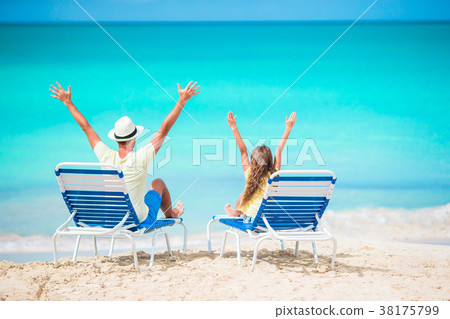 Father and daughter hands up on beach sitting on 38175799