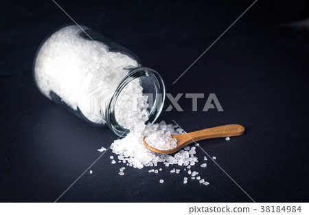 Sea salt with spoon and jar on dark background Sea salt with spoon and jar on dark background 38184984
