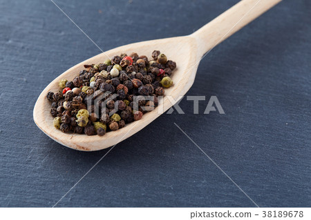 black pepper peas in a spoon on a stone background 38189678