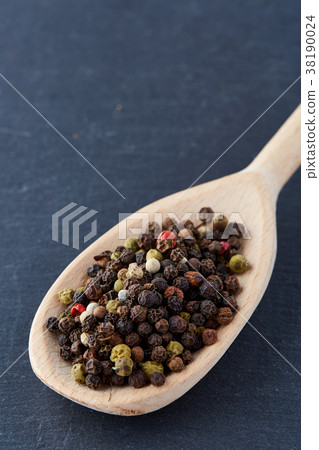 black pepper peas in a spoon on a stone background 38190024