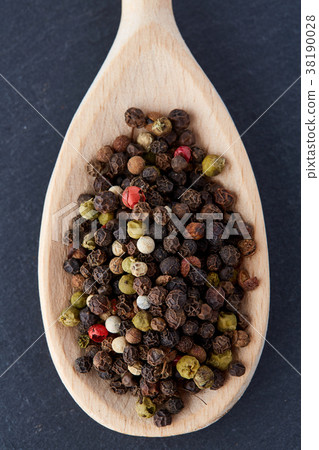 black pepper peas in a spoon on a stone background 38190028