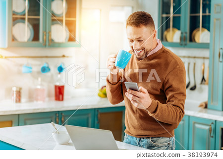 Happy cheerful man holding his smartphone Happy cheerful man holding his smartphone 38193974