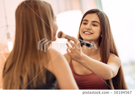 Smiling teenage girl applying makeup to sisters Smiling teenage girl applying makeup to sisters 38194567