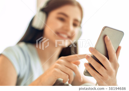 Pleasant teenage girl scrolling her music playlist Pleasant teenage girl scrolling her music playlist 38194686