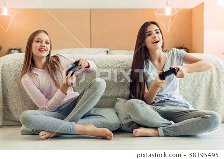Two teenage sisters playing video game in bedroom 38195495