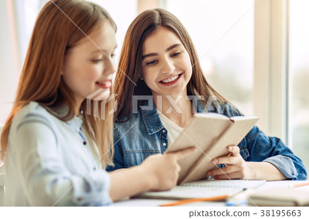 Pleasant sisters reading a book together Pleasant sisters reading a book together 38195663