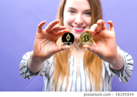 Woman holding physical bitcoin and ethereum coins 38195934