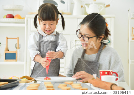 Asian Kid and young mother decorating cookies. Asian Kid and young mother decorating cookies. 38196414