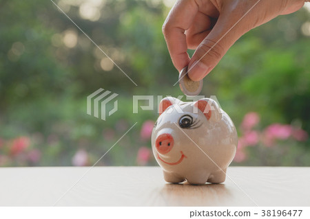 Hand of man holding coin and drop into the piggy. Hand of man holding coin and drop into the piggy. 38196477