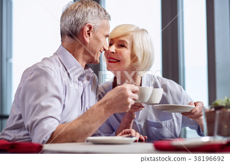 Positive mature couple flirting during coffee Positive mature couple flirting during coffee 38196692