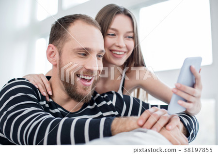 Delighted couple laughing while using the phone Delighted couple laughing while using the phone 38197855