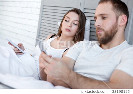 Serious woman looking what her man typing on his Serious woman looking what her man typing on his 38198135