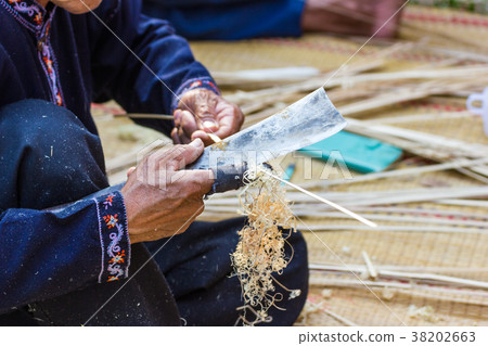 The old man is using a knife to the bamboo 38202663