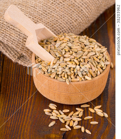 raw rye in a Cup with spoon on a wooden table. raw rye in a Cup with spoon on a wooden table. 38203962