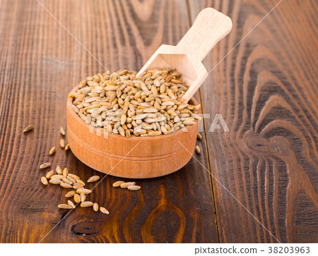 raw rye in a Cup with spoon on a wooden table. raw rye in a Cup with spoon on a wooden table. 38203963