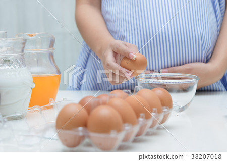 Pregnant woman preparing meal at table 38207018