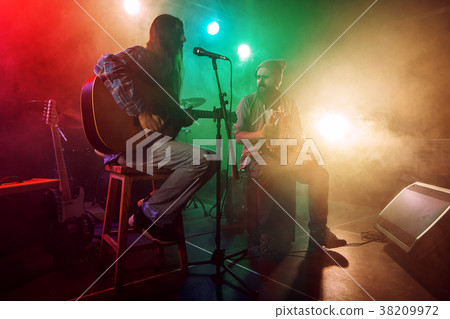 Rock band performs on stage. Guitarist, bass guitar and drums. Rock band performs on stage. Guitarist, bass guitar and drums. 38209972