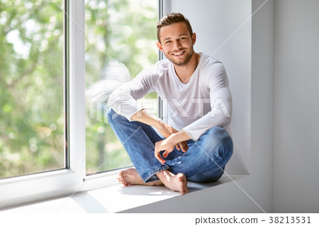 smiling man sitting on window sill in lotus pose smiling man sitting on window sill in lotus pose 38213531