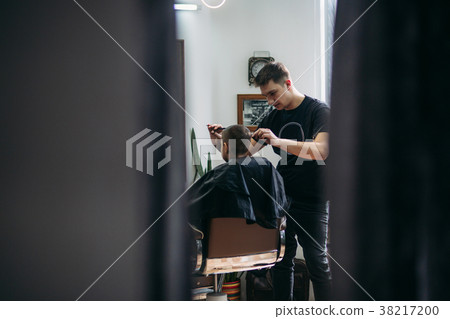 The boy getting haircut by scissor in barbershop The boy getting haircut by scissor in barbershop 38217200