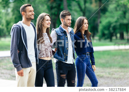 Four young smiling friends relax in park 38217884