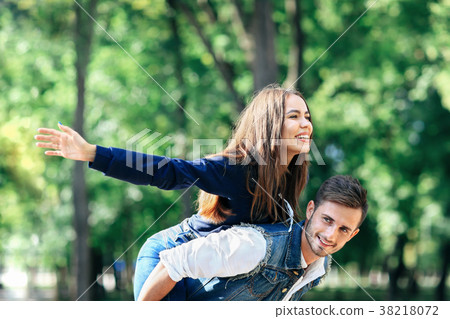 Happy young girl on back of guy portraying bird Happy young girl on back of guy portraying bird 38218072
