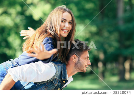 Happy young girl on back of guy portraying bird 38218074