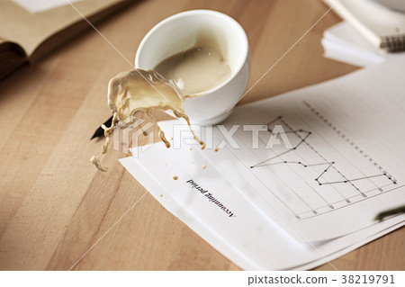 Coffee in white cup spilling on the table in the 38219791