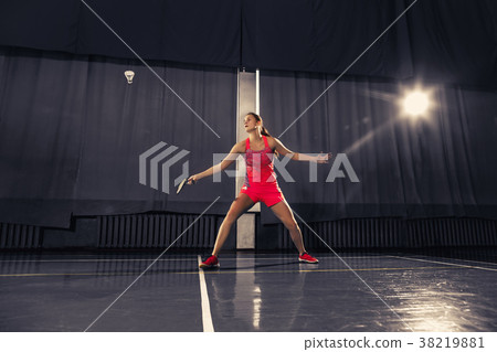 Young woman playing badminton at gym Young woman playing badminton at gym 38219881