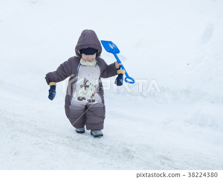 Toddler boy winter Romper plays with a shovel in 38224380