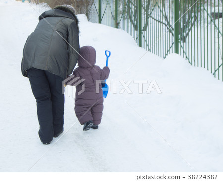 Mother and child with shovel, play in the snow 38224382