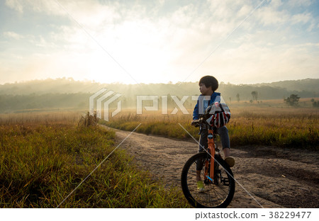 Boy rides a bicycle in the sunrise Boy rides a bicycle in the sunrise 38229477