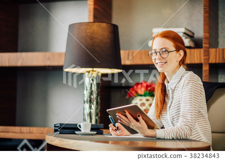 Redhead smiling young female manager using modern Redhead smiling young female manager using modern 38234843