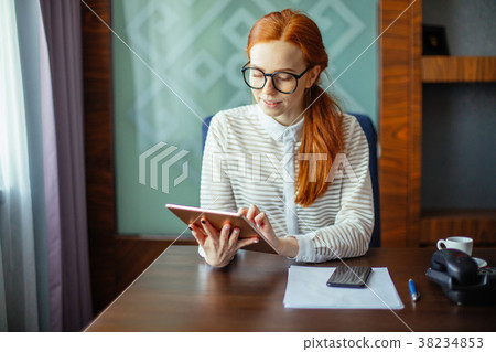 Redhead smiling young female manager using modern Redhead smiling young female manager using modern 38234853