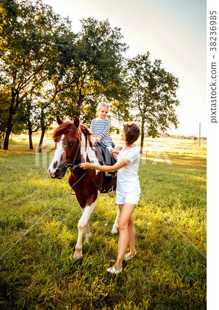 Little girl riding on a horseback with her mother Little girl riding on a horseback with her mother 38236985