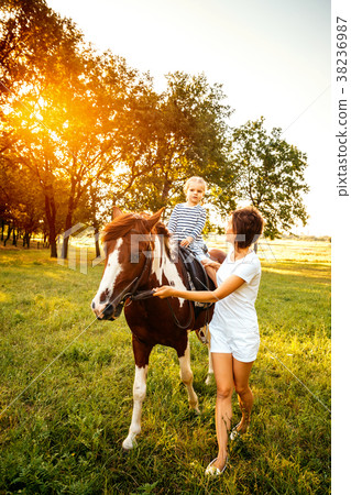 Little girl riding on a horseback with her mother 38236987