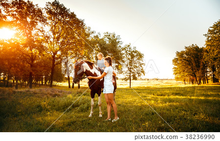 Little girl riding on a horseback with her mother 38236990