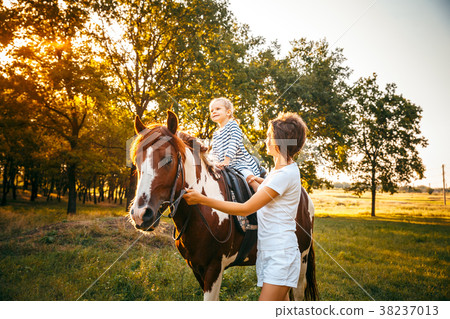 Little girl riding on a horseback with her mother Little girl riding on a horseback with her mother 38237013