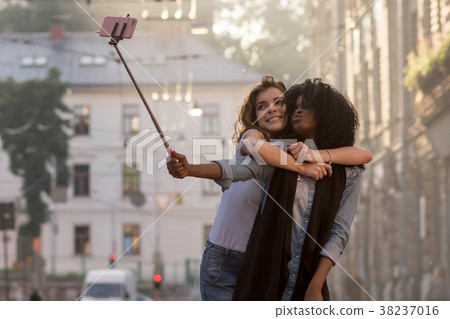 Two friends hugging and making selfie on a 38237016